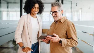Two coworkers looking at a tablet in an office.