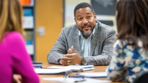 Man talking to two women at table.