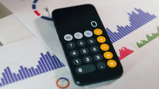 Calculator app on a phone and budget paperwork