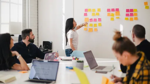 Team in a meeting using sticky notes on a white board.
