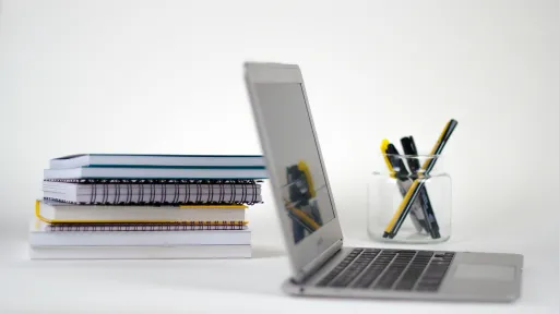 Laptop next to notebooks and pen holder.