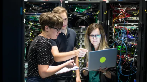 Three people working on servers, photograph.