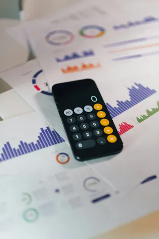 Calculator app on a phone and budget paperwork