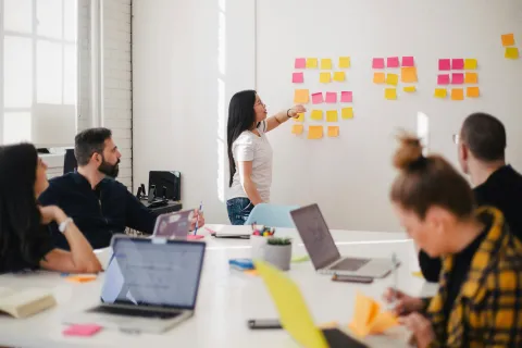 Team in a meeting using sticky notes on a white board.