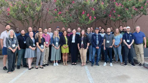 Group photograph of people in front of a tree.