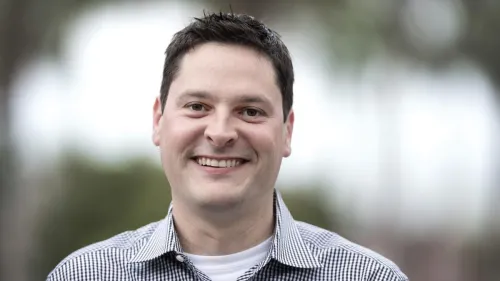Smiling man in a blue and white striped shirt.